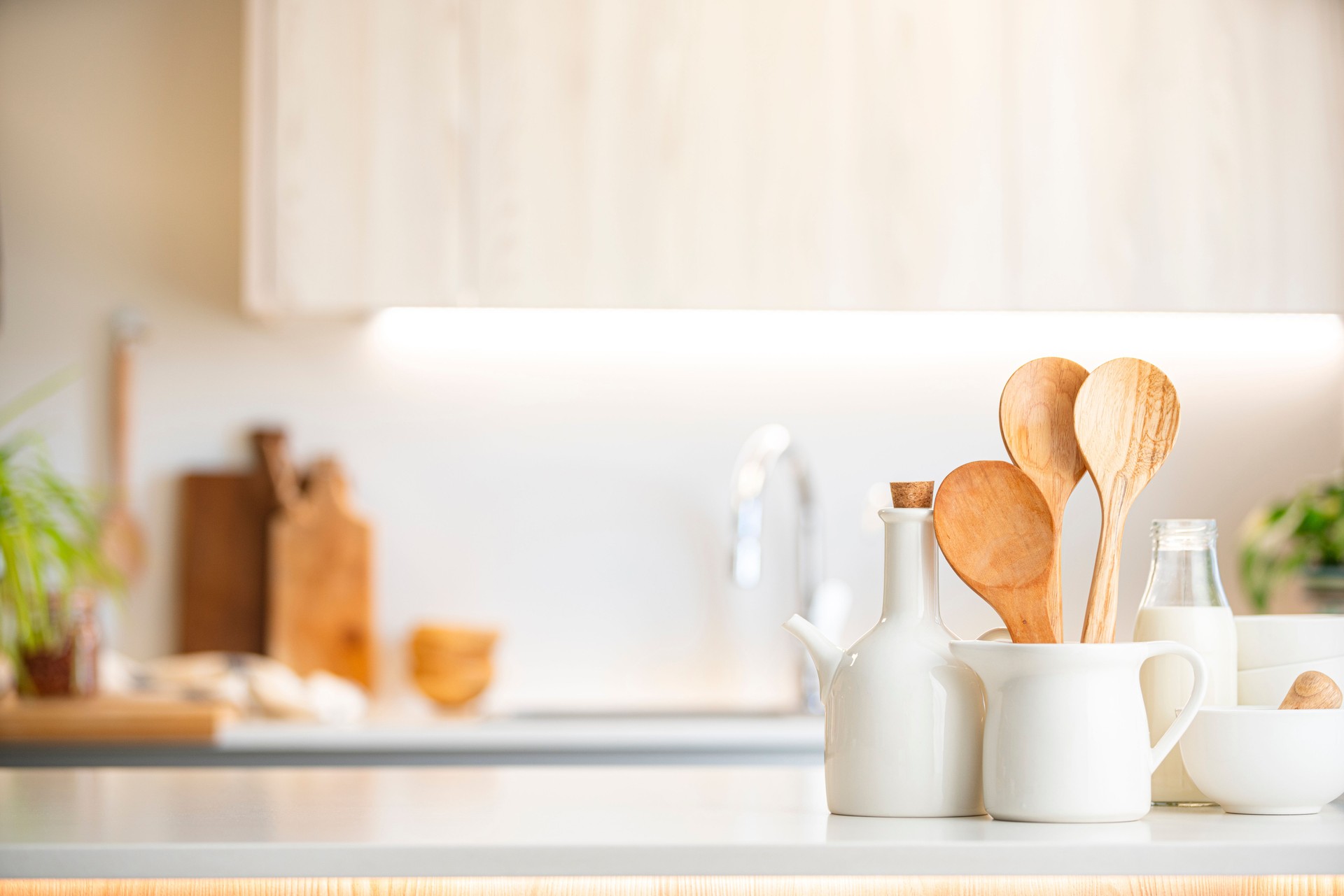 Kitchen counter with white crockery and wooden kitchen utensils. Selective focus on foreground